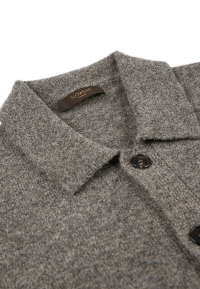 Grau gestrickte Wolle-Kardigan mit Kragen, versehen mit einem Etikett mit der Aufschrift "SLOWEAR" und zwei dunklen Knöpfen auf der Vorderseite.