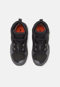 Black athletic shoes with a textured mesh upper, gray accents, padded collar, and bright orange insoles. Laces and reinforced toe cap included.