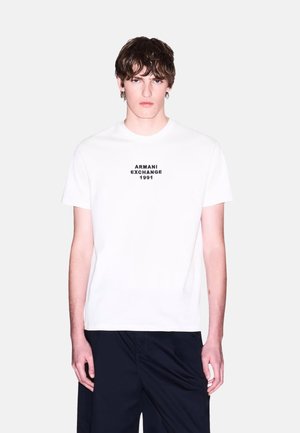 Hvid bomulds T-shirt med et sort trykt logo "ARMANI EXCHANGE 1991" centreret på brystet. Rund hals, korte ærmer, afslappet pasform.
