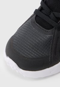 Μαύρο αθλητικό παπούτσι με υφασμάτινο επάνω μέρος υφής, λείες επικαλύψεις και λευκή λαστιχένια σόλα. Διαθέτει μαύρα κορδόνια και ραμμένες λεπτομέρειες.