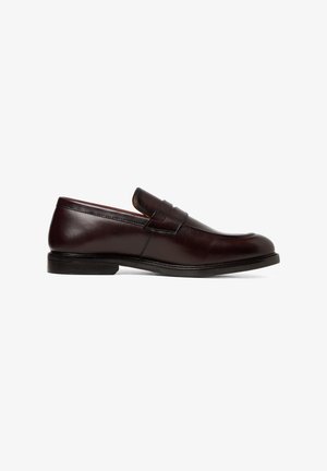 Dark brown leather men's loafer with a low heel, round toe, and decorative strap across the upper, shown in side profile on white background.