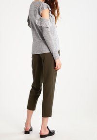 Maglione grigio a maniche lunghe con dettagli di rouches sulle spalle, abbinato a pantaloni cropped verde oliva e scarpe nere slip-on.