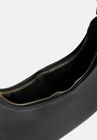 Borsa nera a forma strutturata, con esterno texture e zip dorata. L'interno è foderato in tessuto nero, evidenziando la semplicità.