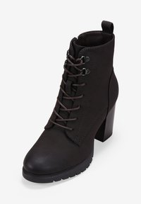 Botín negro de tobillo hecho de material sintético, con cordones en la parte delantera, tacón grueso y suela texturizada para mayor agarre.