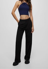 Mörkblå halterneck crop top med ett samlat nackdesign, kombinerad med högmidjade svarta byxor med framveck och sidofickor.