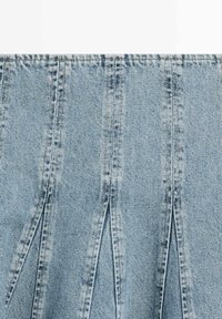 Lichtblauwe denimstof met verticale plooien en zichtbare naadstiksels.