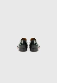 Dark green leather shoes with a polished finish, featuring a low heel and decorative stitching along the back.