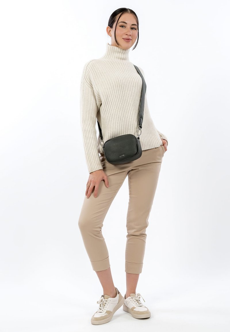 Szara torba na ramię z fakturowanej skóry. Modelka ma na sobie kremowy prążkowany golf, beżowe spodnie o długości przed kostkę oraz białe trampki.