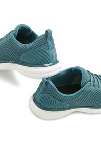 Chaussures de sport teal avec dessus en maille, accents texturés et semelles blanches. Les caractéristiques comprennent un col rembourré et une languette au niveau du talon.