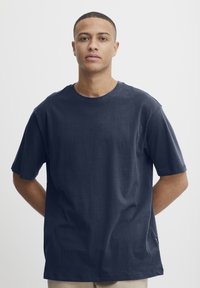 Tengerészkék, crew-neck, rövid ujjú póló puha anyagból, amely laza szabású és minimális varrási részletekkel rendelkezik, látható logók vagy minták nélkül.
