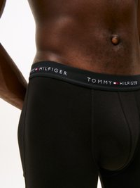Fekete pamut boxer alsónadrág, szoros illeszkedéssel, a "TOMMY HILFIGER" fehér betűkkel díszített márkás elasztikus derékkal és egy kis logó részlettel.