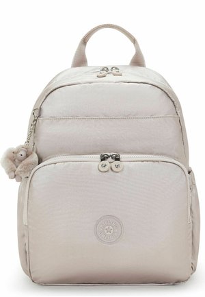 Sac à dos Kipling beige clair avec poche avant zippée, fermetures à double fermeture éclair, poignée supérieure, et un porte-clés peluche singe attaché sur le côté.