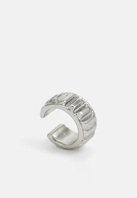 Anillo de plata con un diseño texturizado y estriado. Con extremos abiertos; interior liso, acabado brillante. El diámetro se adapta a varios tamaños de dedo.