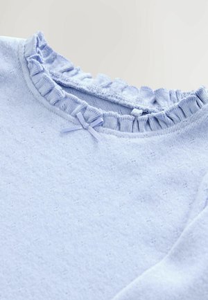Haut à manches longues bleu clair avec un col en dentelle texturé et un petit nœud en satin au niveau de l'encolure. Matière douce en coton.