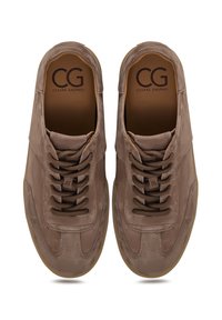 Zapatillas de ante marrón con una textura suave, que cuentan con cinco pares de cordones marrón oscuro y una suela de goma. Marca visible en el interior de los zapatos.
