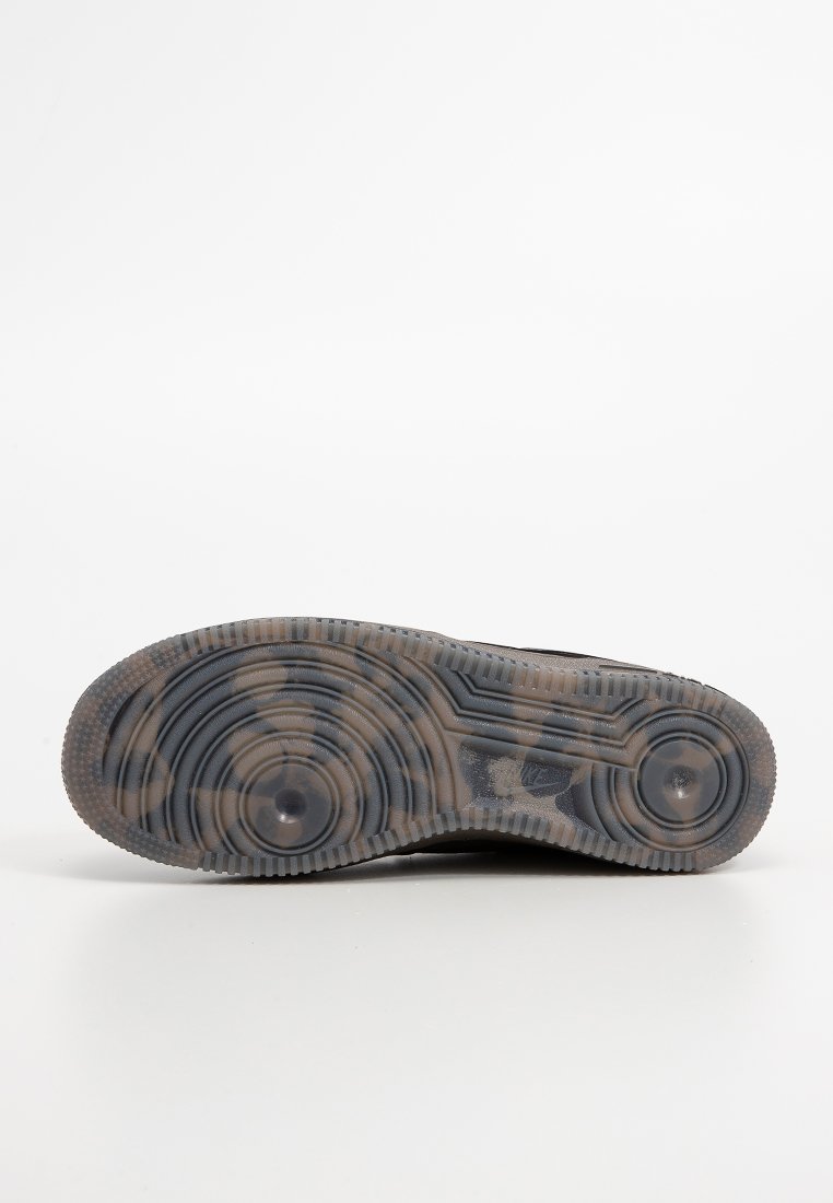 Suela de zapatilla negra con surcos decorativos y acentos circulares. Hecha de goma, presenta superficies texturizadas y un aspecto desgastado.