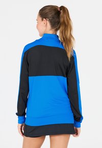 Svart och blå pulloverjacka med hög krage, långa ärmar och färgblockdesign. Slät textur och avslappnad passform.