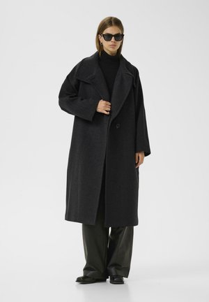 Long, dark grey coat made of wool blend, featuring a wide collar, oversized fit, single button closure, and large, loose sleeves.