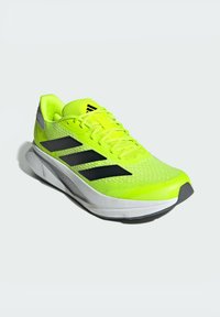 Lime green athletic shoe with a breathable mesh upper, three black stripes along the side, white midsole, and gray heel accent.