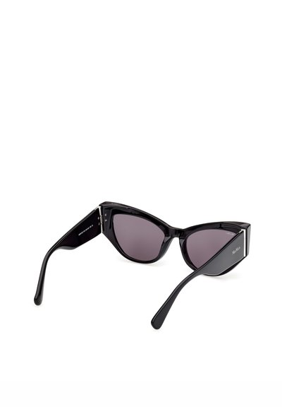 Lunettes de soleil noires à monture œil de chat avec des verres foncés et des branches épaisses, présentées en angle arrière sur un fond blanc.