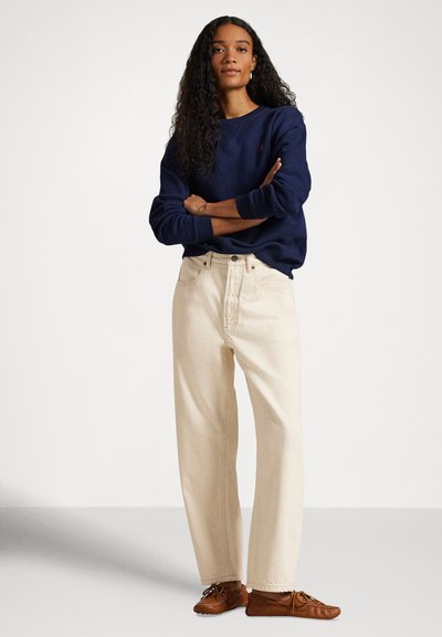 Μπλε ναυτικό φούτερ, εκρού παντελόνια με φαρδιά μπάτσα και καφέ παπούτσια με κορδόνια. Λείο ύφασμα, άνετη εφαρμογή και απλός σχεδιασμός χωρίς ορατά σχέδια.