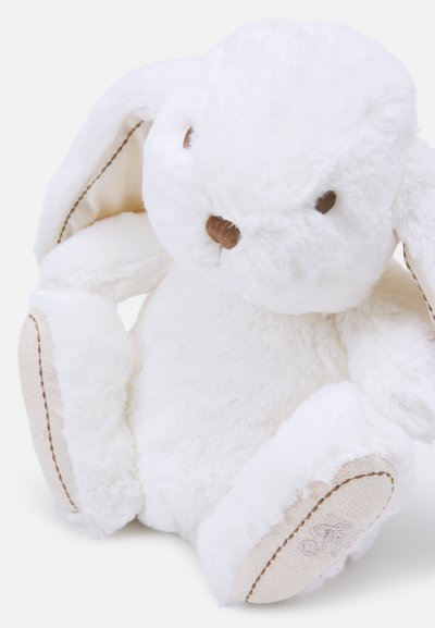 Jouet en peluche blanc en forme de lapin avec une fourrure douce, de longues oreilles et des accents marron sur les yeux et le nez. Il possède un fond beige cousu avec un logo.