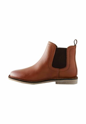 Brun læder Chelsea-støvle med sort elastisk sidepanel, trækstrop ved hælen og lav tekstureret sål på hvid baggrund.
