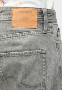 Jeans din denim gri, cu o etichetă din piele cu "JACK & JONES" pe talie, cusături în contrast și un design clasic cu cinci buzunare.