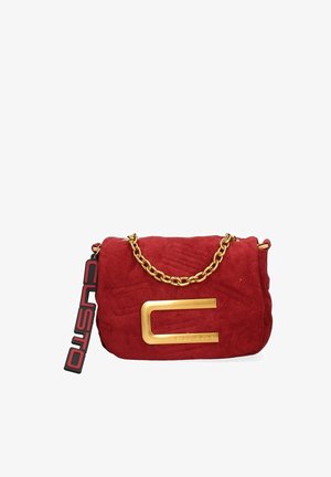 Red suede handbag with a quilted design, gold chain strap, and a prominent gold hardware accent featuring the letter "C" with attached tag.