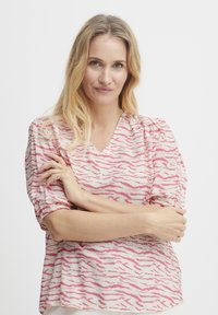 Gaiši rozā puff-sleeve blūze ar baltu zebru svītru rakstu. Iespējas: V-veida kakls un elastīgas aproces, izgatavota no mīksta auduma.