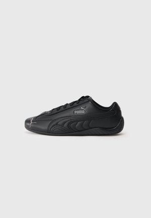 Baskets basses noires Puma avec fermeture à lacets, design latéral incurvé et logo Puma près du talon et des orteils, vues de profil sur fond clair.