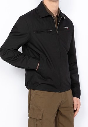 Black zip-front jacket with a classic collar, featuring a chest pocket and side pockets. Made of smooth fabric with a relaxed fit.