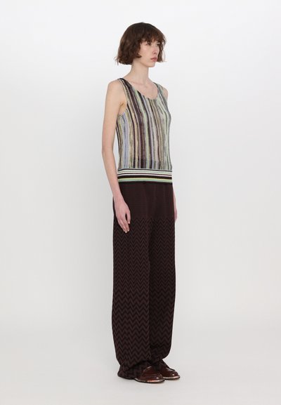 Multicolored knit tank top with a striped pattern and subtle sheen, paired with wide-leg brown zigzag patterned trousers and brown shoes.