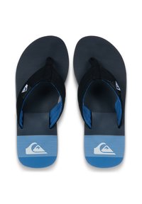 Μαύρα και μπλε σαγιονάρες με μαύρη υφασμάτινη σόλα, μπλε λουριά και λευκό λογότυπο. Η σχεδίαση περιλαμβάνει ένα βαθμιδωτό μοτίβο στην επιφάνεια του πέλματος.