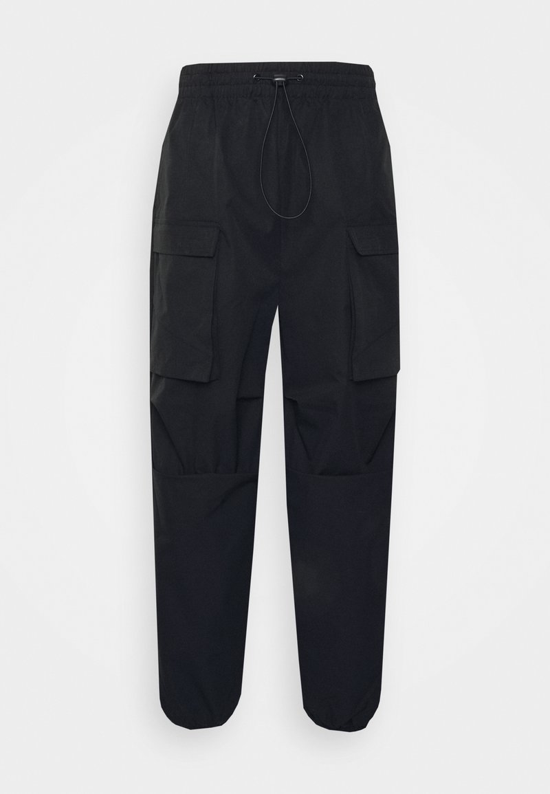 Pantalon cargo noir avec taille élastique et cordon, avec grandes poches à rabat sur les cuisses et poignets élastiques aux chevilles.