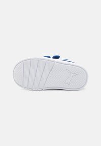 Suela de zapatilla blanca con acentos azules. Presenta estrías horizontales y un patrón de tracción en zigzag. Logo en relieve en el área del talón.