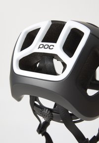 Casque noir avec des accents blancs, doté de trous de ventilation, de sangles ajustables et d'une doublure intérieure texturée. Logo de la marque visible.