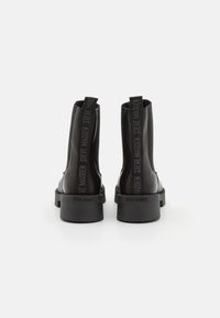 Botines de cuero negro con un diseño elegante, que presentan una suela de plataforma gruesa y tiradores de tela con la marca "STEVE MADDEN".