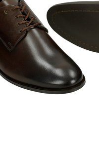 Dunkelbraune Herren-Lederschuhe mit Schnürsenkeln, glatter Oberfläche und sichtbaren Nähten an der Sohle.