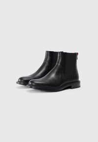 Black leather Chelsea boots with elastic side panels, rounded toes, and low block heels. Features red accents on the pull tabs.