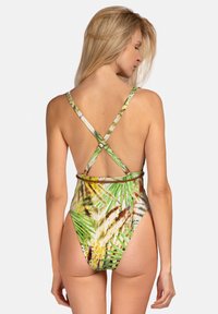 Jednoczęściowy kostium kąpielowy z żywym wzorem palmowych liści w zielonym i żółtym kolorze, z krzyżującymi się ramiączkami na plecach i wysokim krojem nogawek.