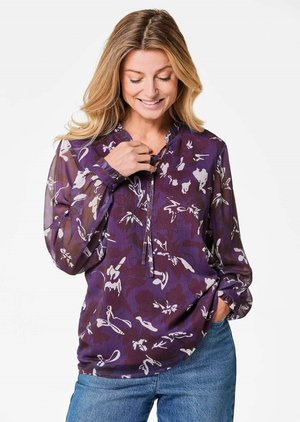 Lila Bluse mit Blumenmuster, leichtes Material, lange Ärmel und eine halbe Knopfleiste. Akzentuiert mit elastischen Bündchen und einem lockeren Schnitt.