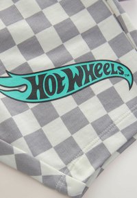 Grau-weiß kariertes Stoffmuster mit einem blauen und schwarzen "Hot Wheels"-Logo, das eine glatte Textur und genähte Kanten aufweist.