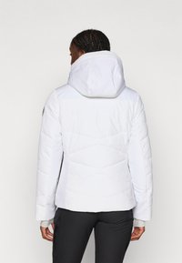 Fehér puff jacket, testhez simuló fazonnal, kapucnival, steppelt kialakítással és bordázott mandzsettákkal, könnyű, vízálló anyagból készült.