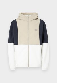 Kleurgeblokte jas met een beige bovenstuk, marineblauwe mouwen en een witte onderkant. Inclusief een capuchon en een rits aan de voorkant. Lichtgewicht materiaal.