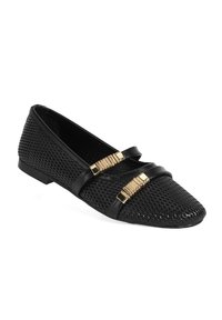 Chaussure noire à enfiler avec une tige en maille texturée. Dotée de deux straps noirs avec des accents en métal doré et d'une semelle profil basse.