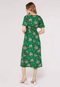 Grün gemustertes Midi-Kleid mit kurzen Ärmeln, tailliertem Bund und verstreuten, bunten Blumenmustern. Glattes, leichtes Material.