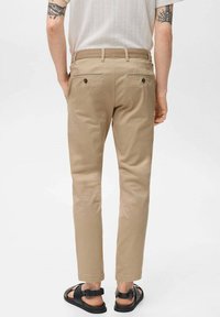 Chino khaki con tasche posteriori, slim fit. Indossati con sandali neri. Tessuto leggero e testurizzato; vita su misura e orli ordinati.