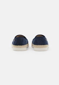 Scarpe slip-on blu navy con texture perforata, suola in espadrille intrecciata beige a contrasto e piccolo logo sul tallone.