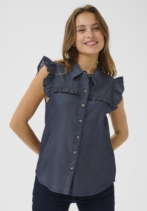 Sötétkék farmering fodros válldíszítéssel és elülső gombolással. Galléros nyakkivágással és ívelt szegéllyel rendelkezik.